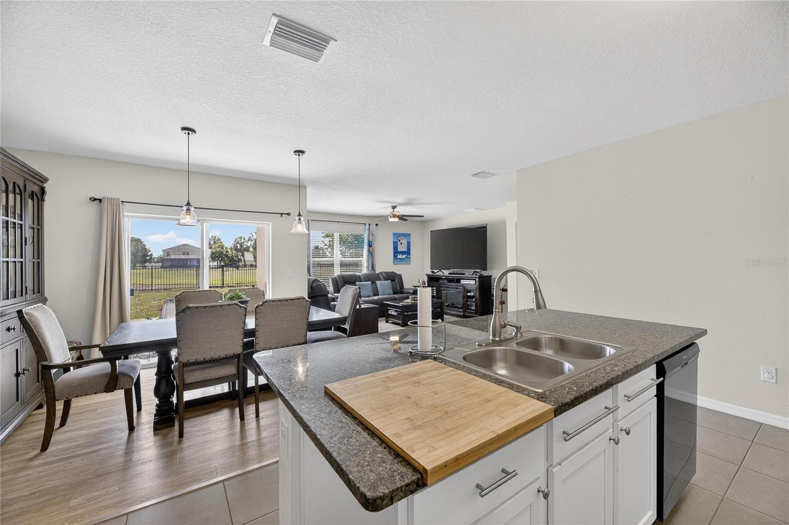 Spacious family and dining room combo featuring luxury vinyl flooring and sliding glass doors leading to the backyard and covered lanai.