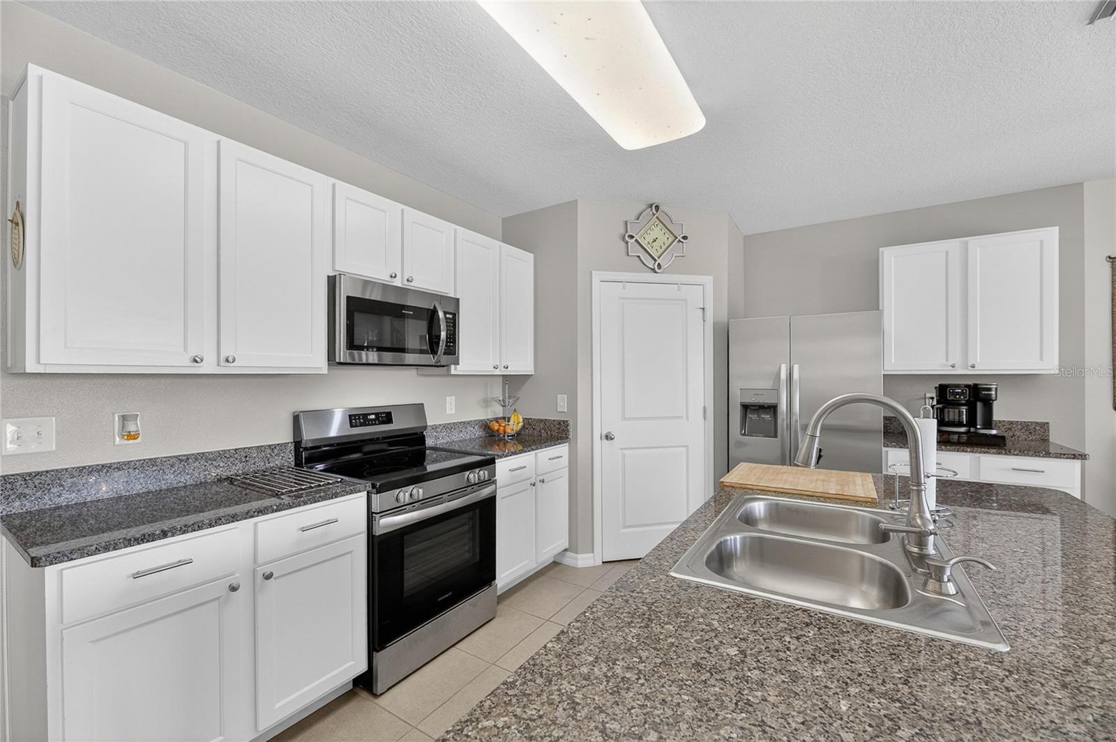 Beautiful white shaker-style cabinets paired with granite countertops and newer stainless steel appliances create a bright and modern kitchen.