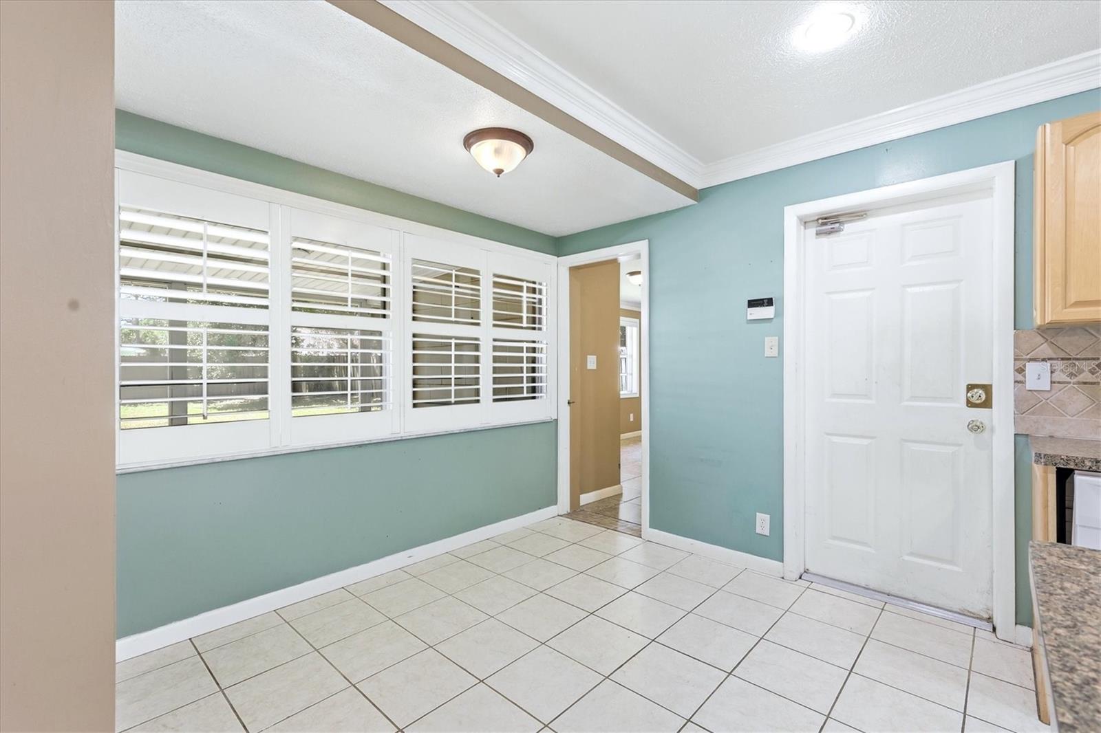Family room is spacious and has crown molding, a ceiling fan and access to the back patio and yard