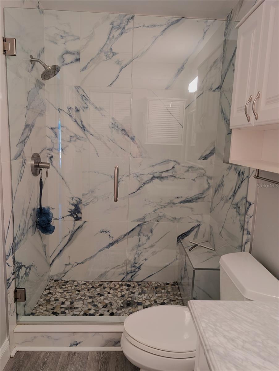 Totally renovated guest bathroom features gorgeous shower with bench, glass shower door and grab bars as well as new comfort height commode.