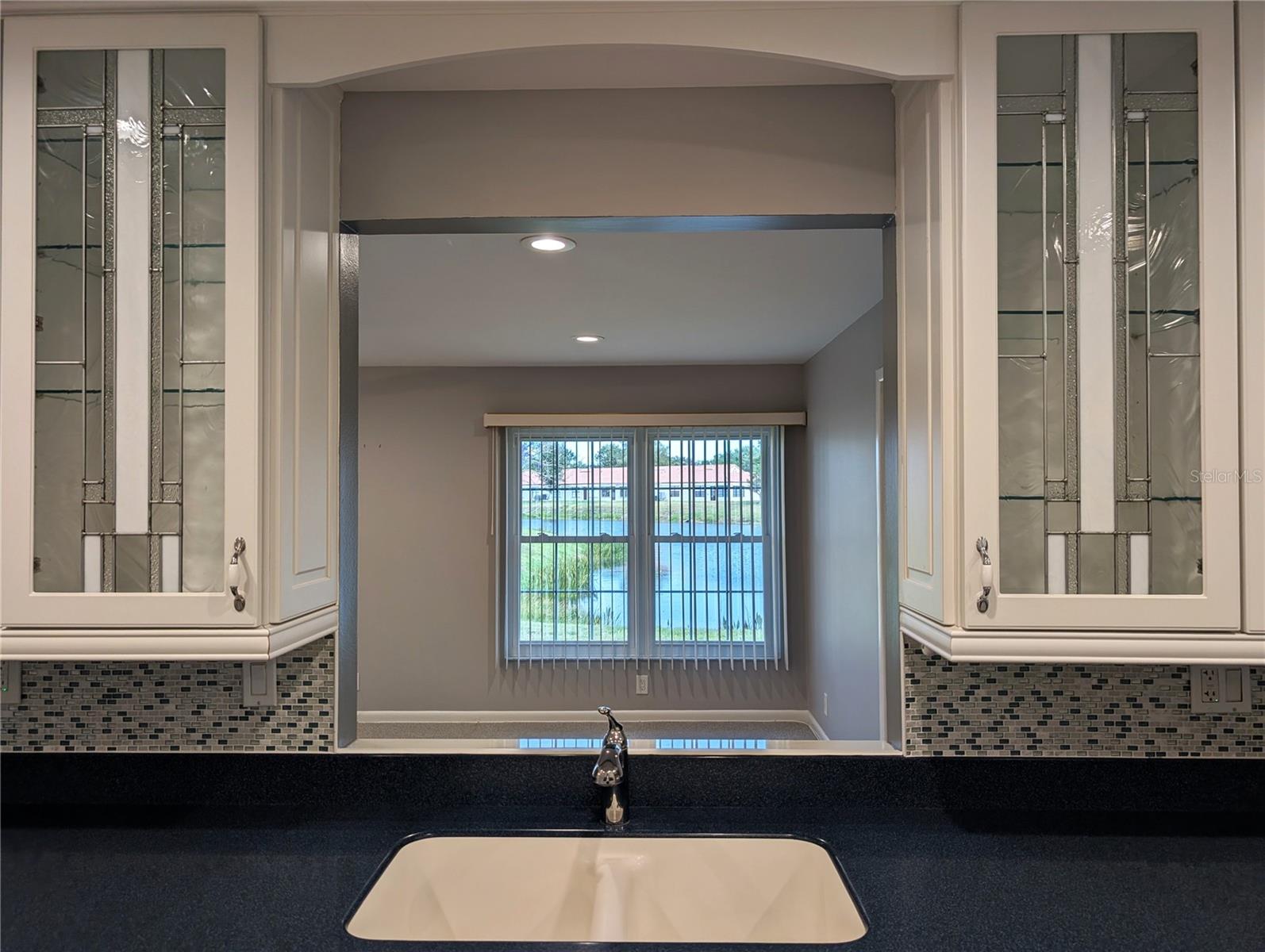 Kitchen pass thru window is framed by two stunning leaded/stained glass cabinet doors. A simply beautiful design and focal point. Beautiful view from kitchen to backyard to enjoy while working in the kitchen.