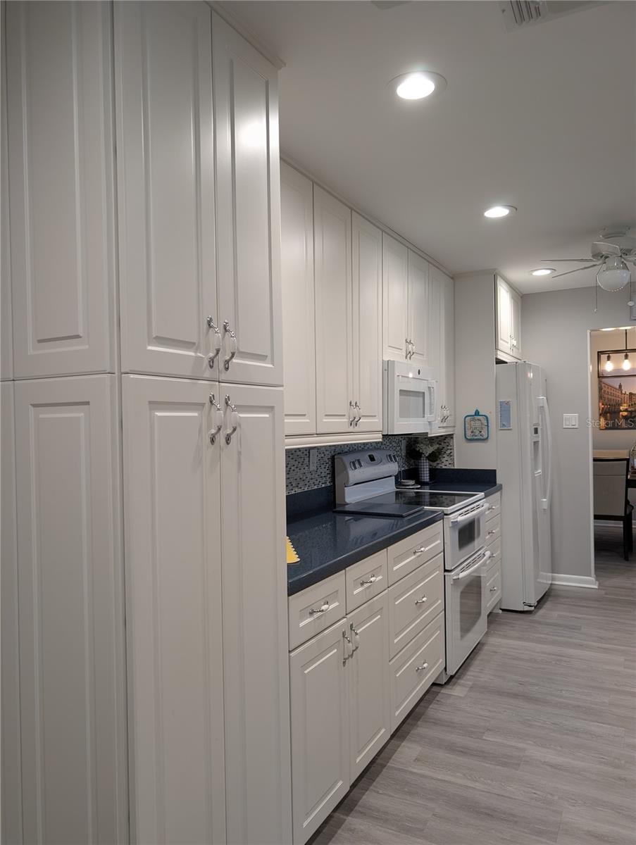 New kitchen design provides extra countertop workspace and additional cabinets for extra storage. White appliances include Maytag double oven, glass top range and new GE microwave hood (2020). GE side by side refrigerator features in door water/ice dispenser.