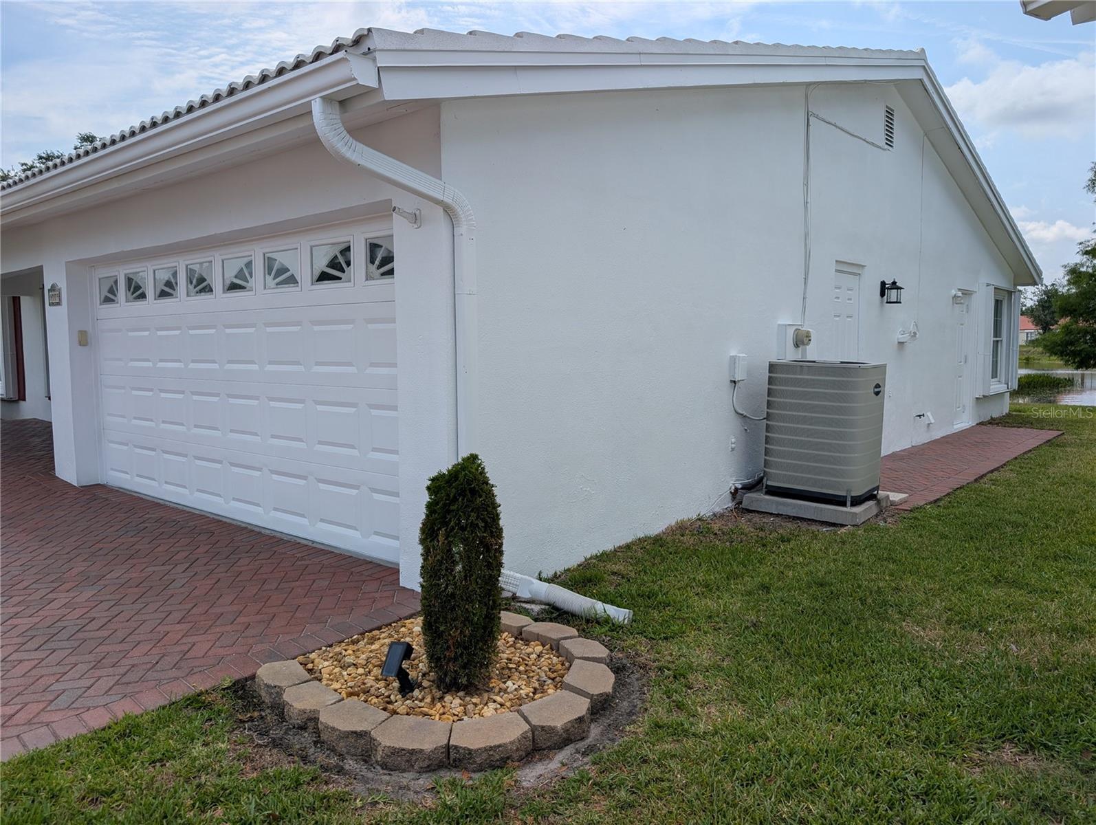 Exterior side view. Updated side garage man-door w/new exterior light has direct access to side yard.