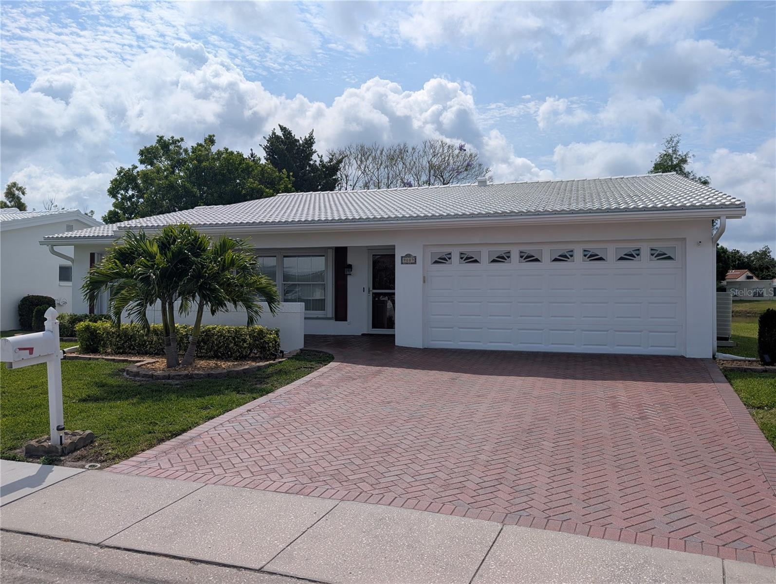 Exterior front view of garage. Exterior features include new tile roof (2020), gutters/downspout, Paver driveway/front porch/side patio (2016), double pane windows (2005) and accordion storm shutters (2007).