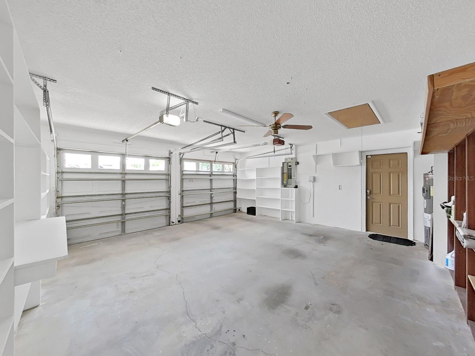 2 Car Garage, lots of shelving all around. Water heater is 2023 model. And attic pull down stairs.