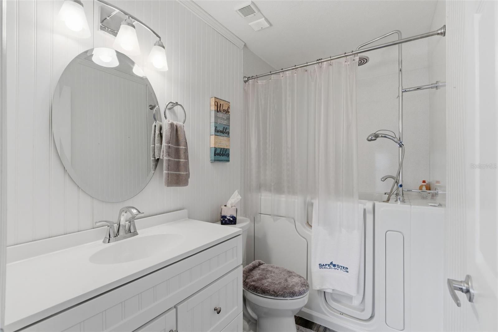 guest ensuite is beautifully finished with beadboard-style wall detailing, a bright vanity area, and a Safe Step walk-in tub with jacuzzi jets for added comfort, relaxation, and convenience.