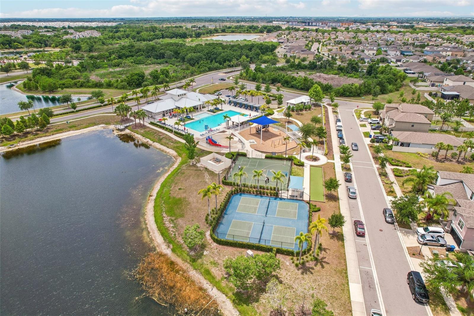 PLENTY TO KEEP THE FAMILY ENTERTAINED!! AMENITY AERIAL OVERVIEW OF TENNIS COURTS, BASKETBALL, PLAYGROUND AND WATER PARK