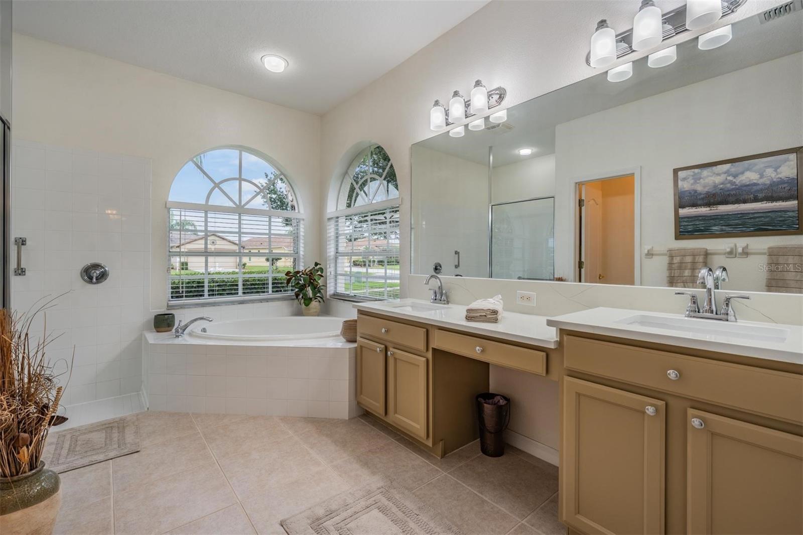 Corner soaking tub and built in vanity seating in updated primary bathroom