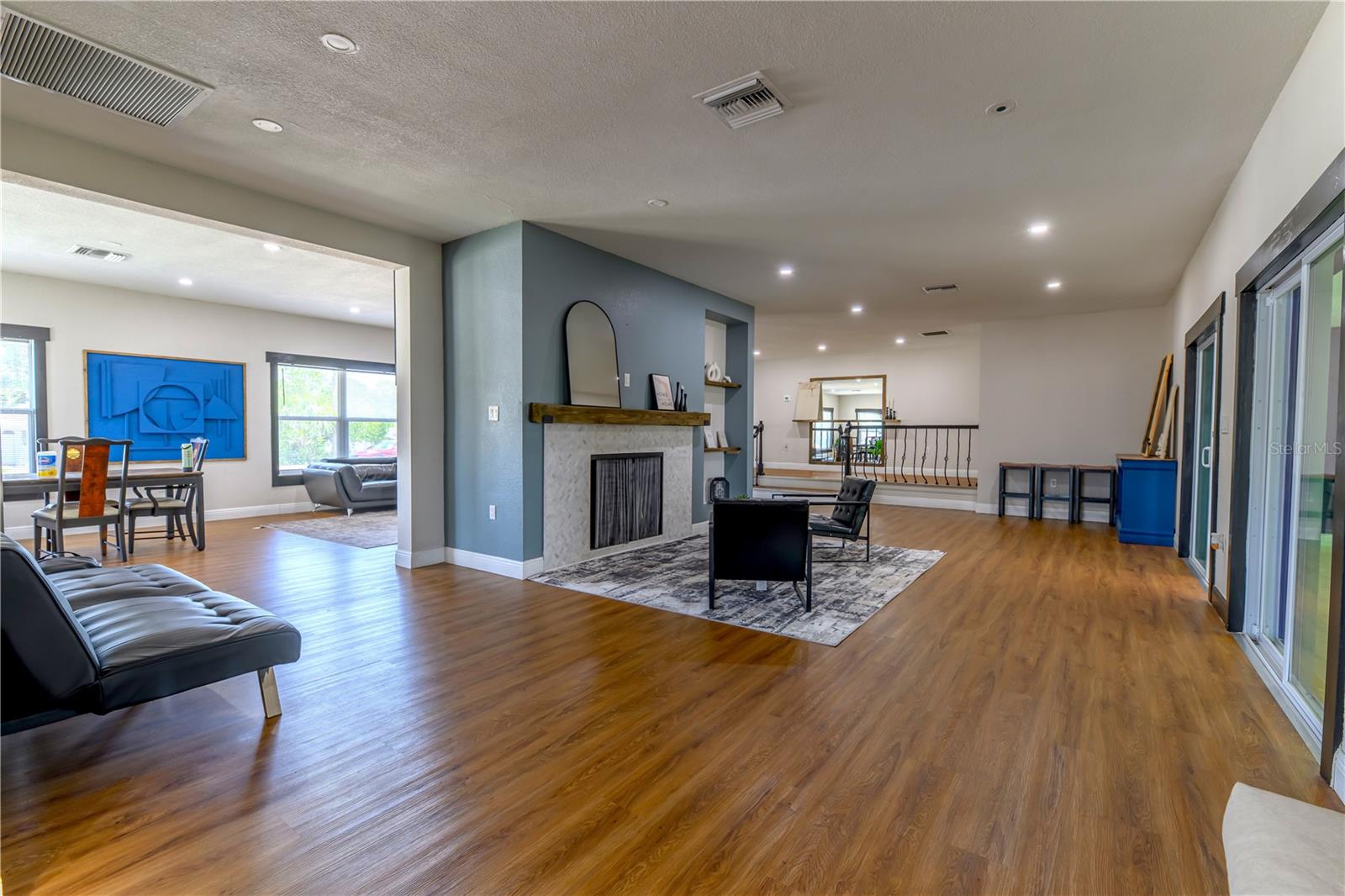 Left to Right:  Dining/Living Room, Fireplace Sitting Area/2nd Living Room Space, (2) Step up Platform to Primary Bedroom on Left & Bedroom 2, 3, & Main Bathroom to the Right, and Sliding Glass Doors leading to the Florida Room