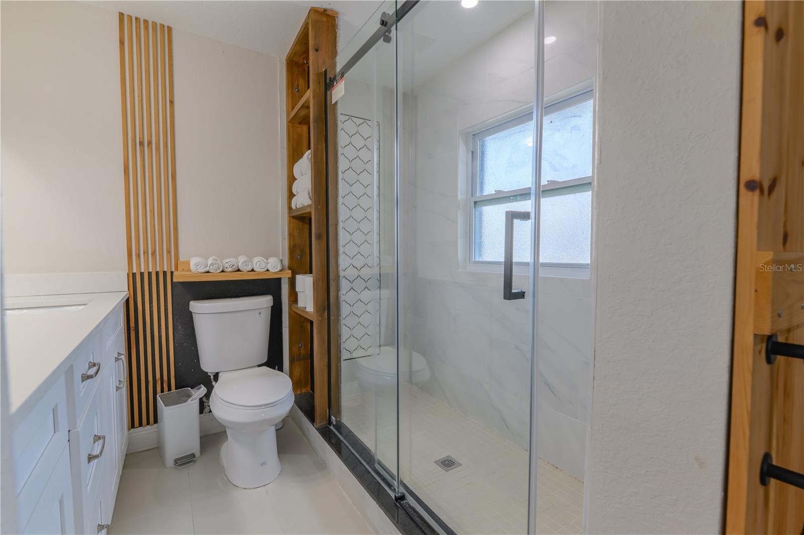 Primary Ensuite Toilet, Wood Slat Wall Accents & Shelving, Shower with Glass Doors