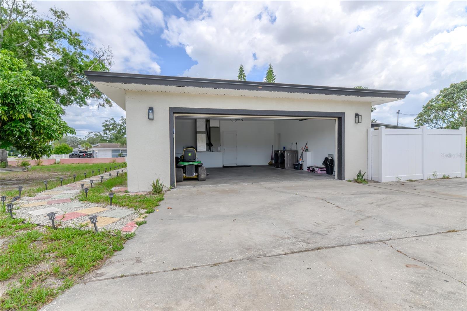 Left to Right:  Pavers along the side of the house leading to the Front Door, 2-Car Garage Open, Air Handler, Entry Door, Washer & Dryer