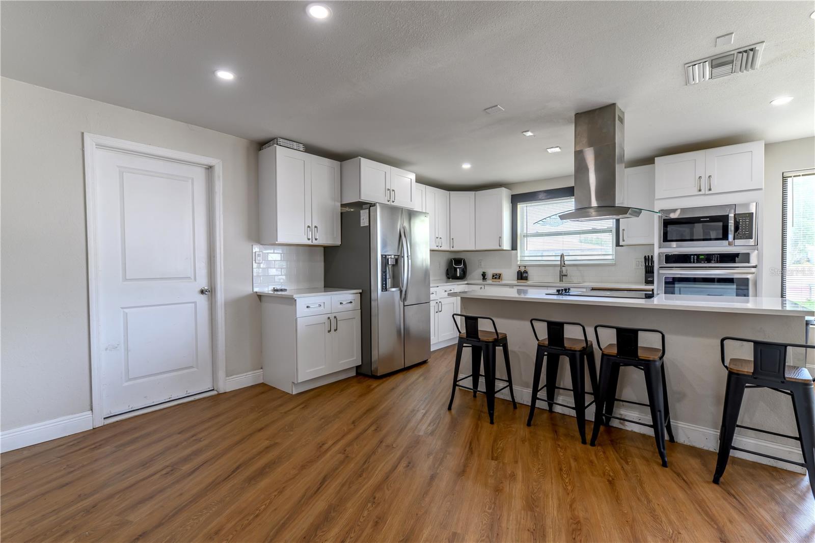 Interior Garage Door Entry into Open Kitchen Concept with Stainless Steel Appliances
