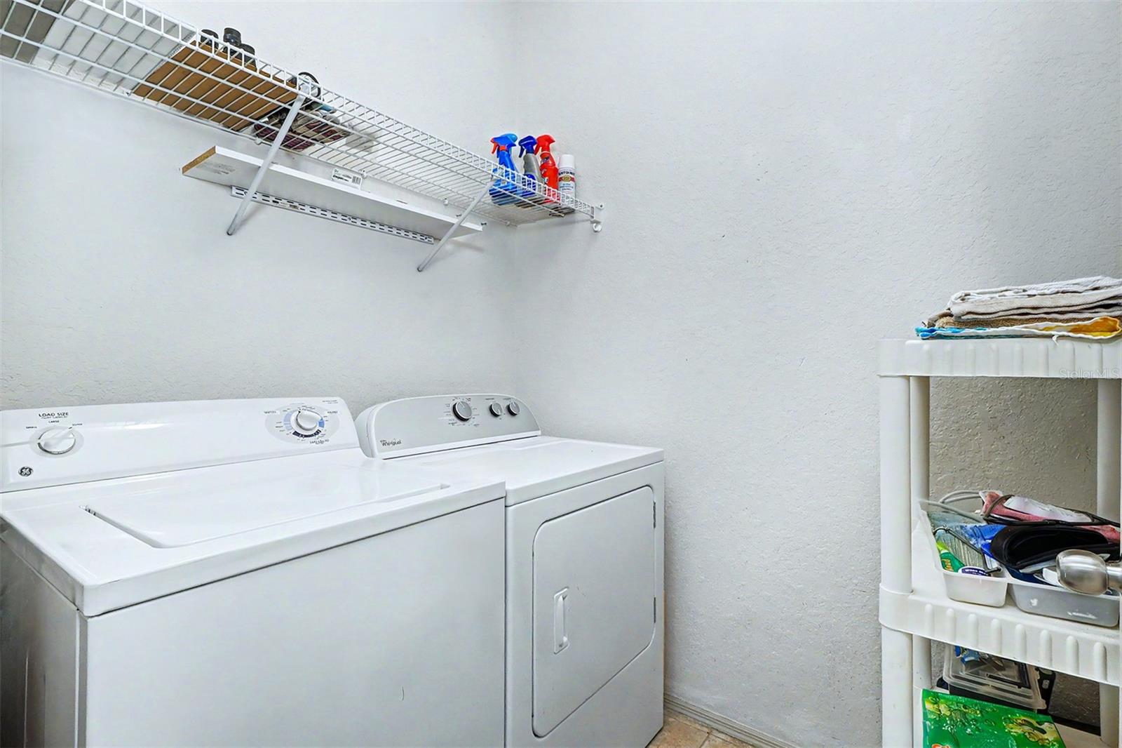 Laundry room with full size washer and dryer and storage shelf