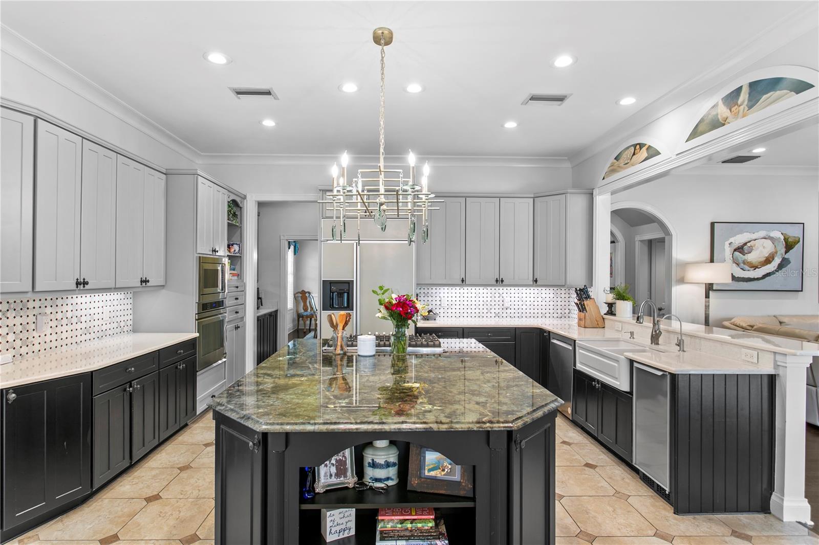 The kitchen features a large island with exotic granite, quartz countertops, warming drawer, wine refrigerator, abundant prep space, and a large walk-in pantry.