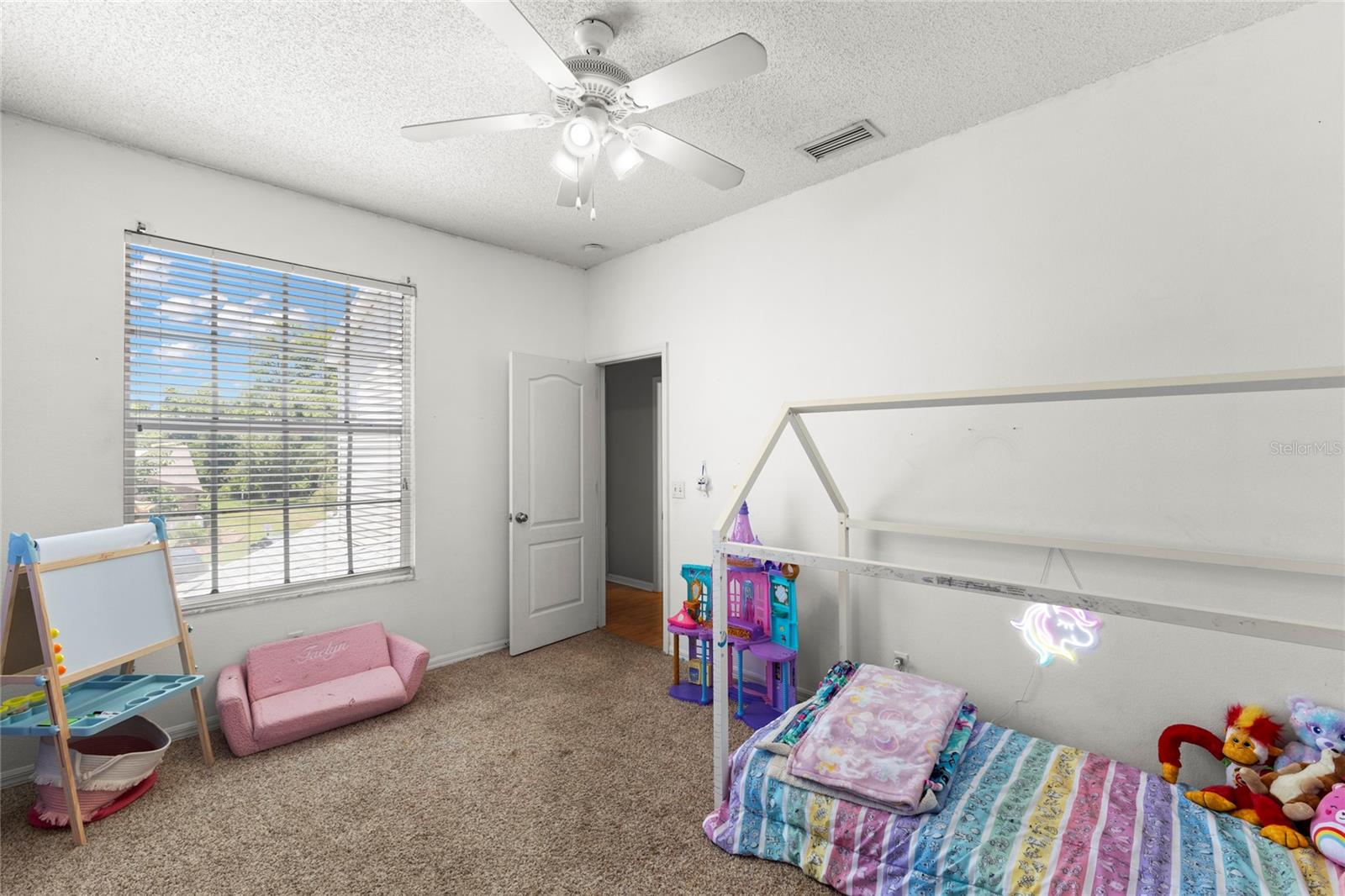 Bedroom 2 features carpeted flooring, walk-in closet, ceiling fan with light kit, and oversized window providing natural light. Flexible layout accommodates bedroom furnishings, nursery setup, playroom use, or guest accommodations.