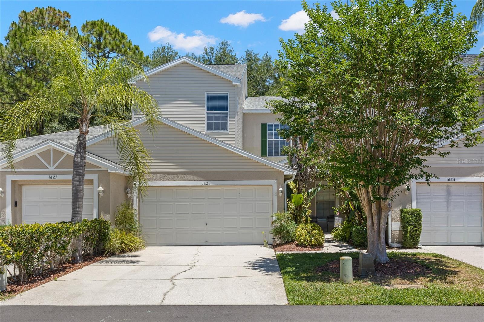 3-bedroom, 2.5-bath, two-story townhouse with a covered entry, neutral exterior palette, mature landscaping, and a two-car garage with an extended driveway for additional parking. Located within the East Lake Landings community with sidewalks, maintained grounds, and a low-maintenance homesite.