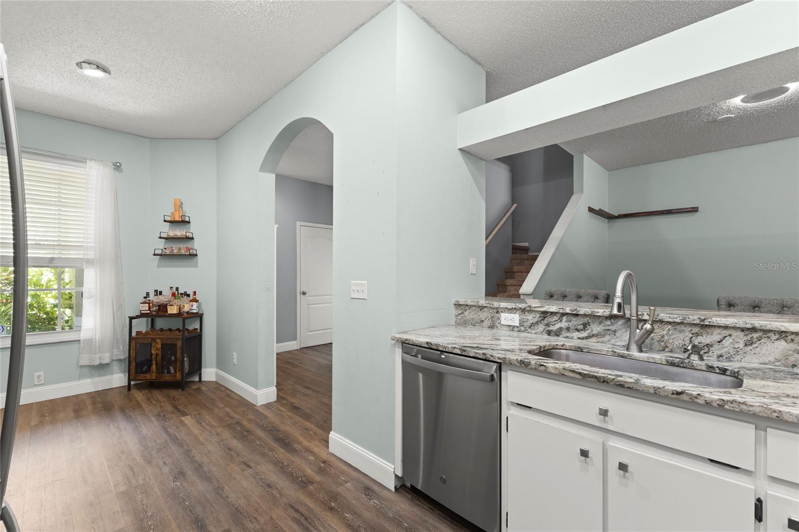 The kitchen layout offers an ideal spot for a breakfast table, while arched openings and elevated bar seating reinforce the home’s open-concept design.