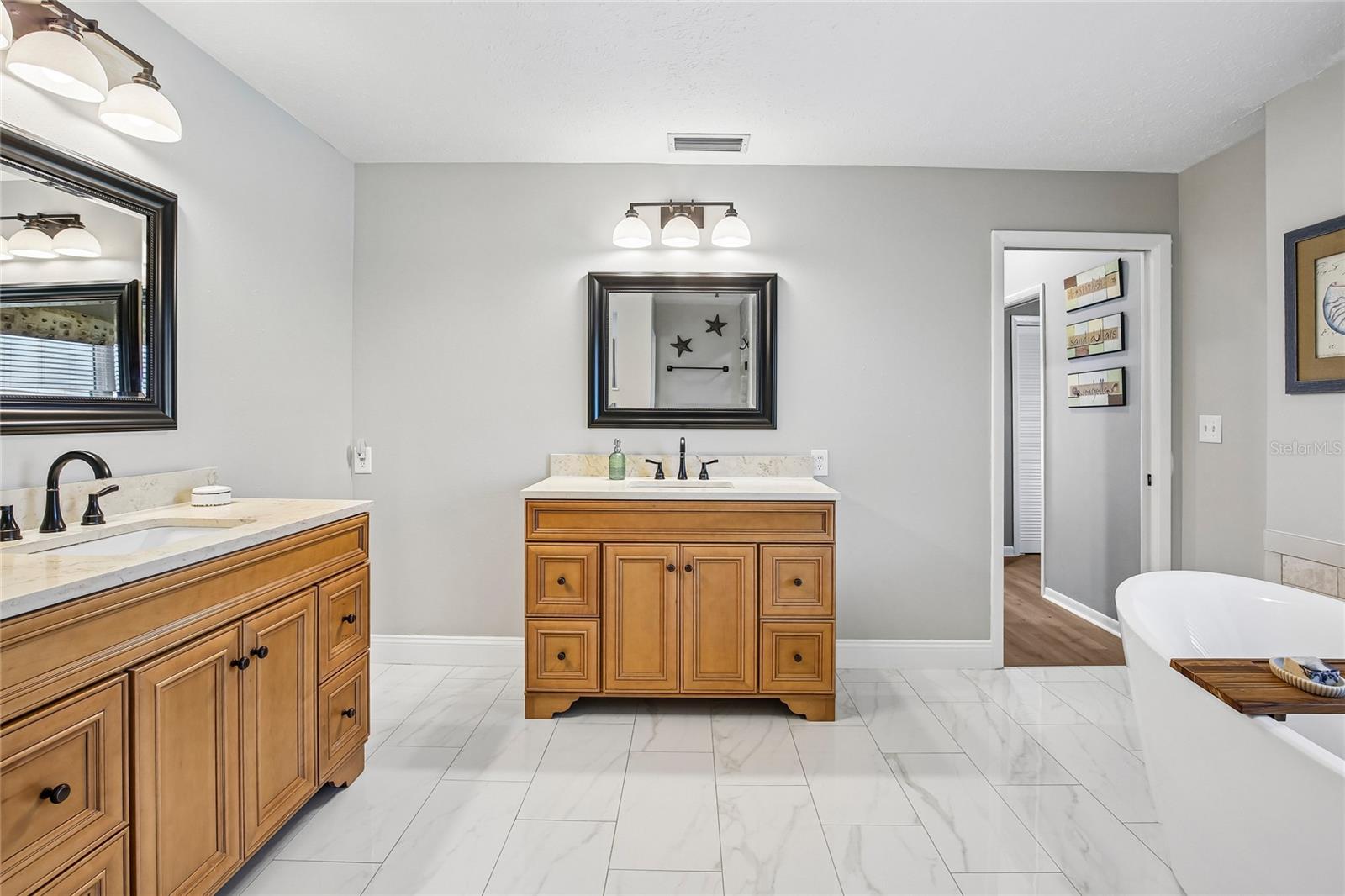 Primary Bathroom with marble floors, free standing tub, 2 large vanities and a walk in shower