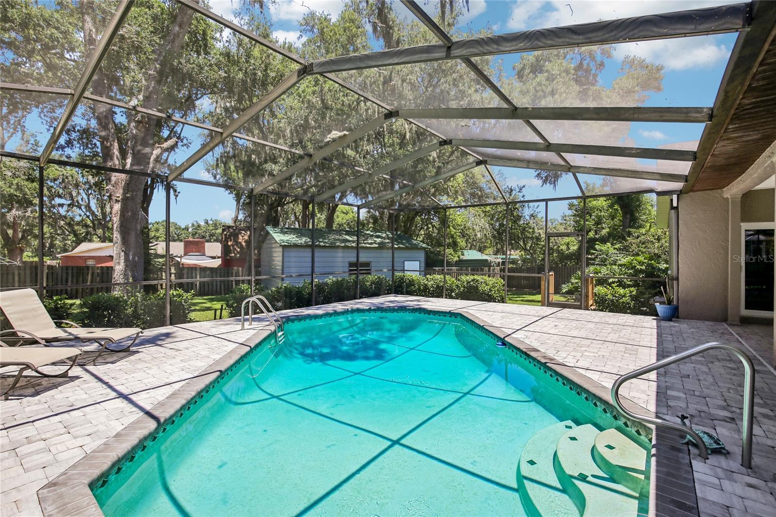 View of pool, pavers and backyard