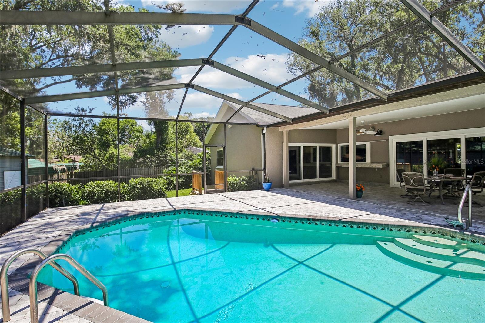 View of pool, pavers and backyard