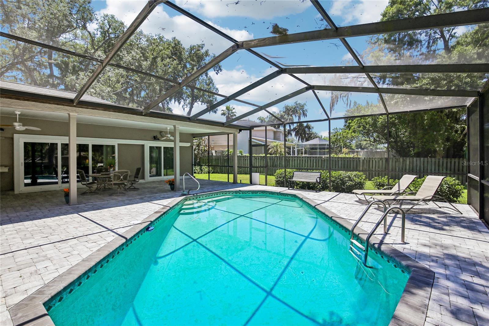View of pool, pavers and backyard