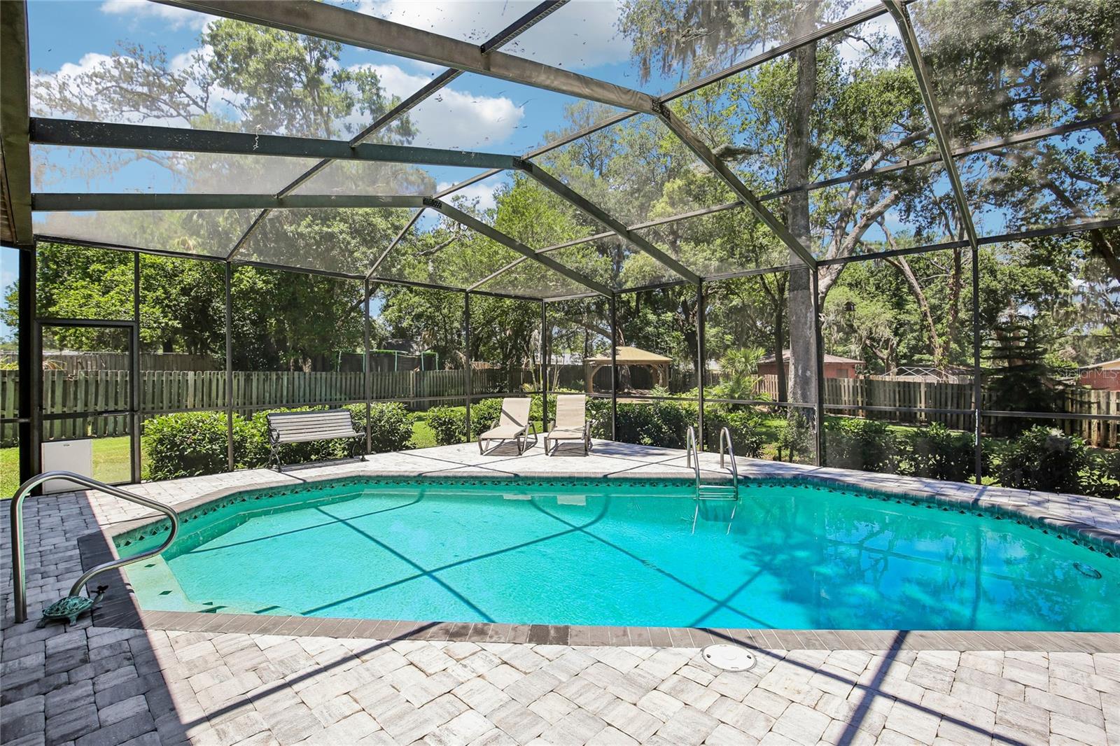 View of pool, pavers and backyard