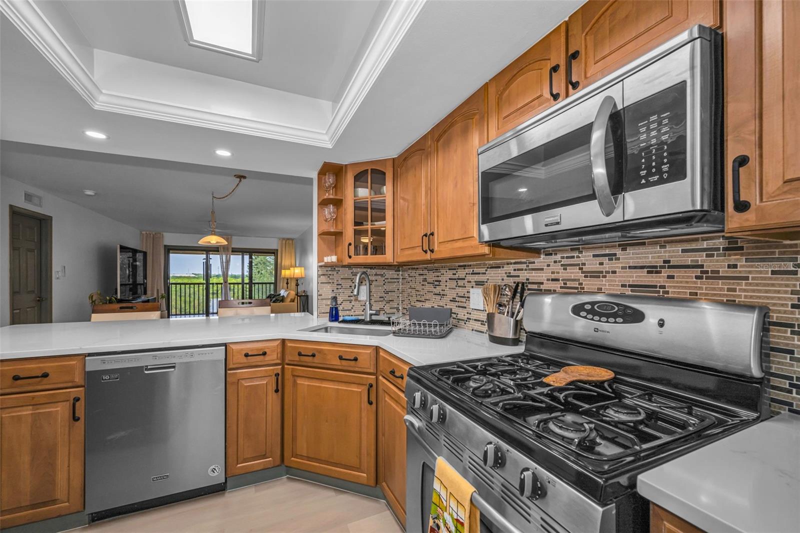 Kitchen with gas range, microwave, dishwasher, new backsplash, new overhead lighting, new Quartzite countertop.