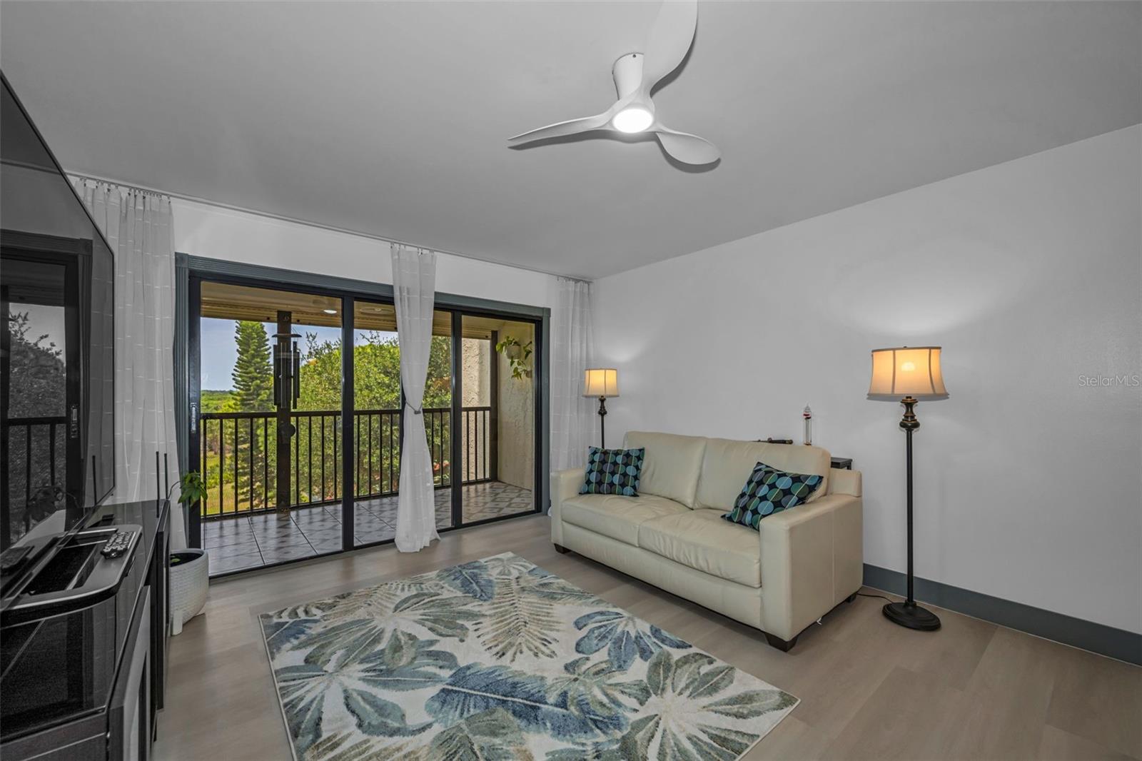 Living room with new fans view of lush landscaping from balcony.