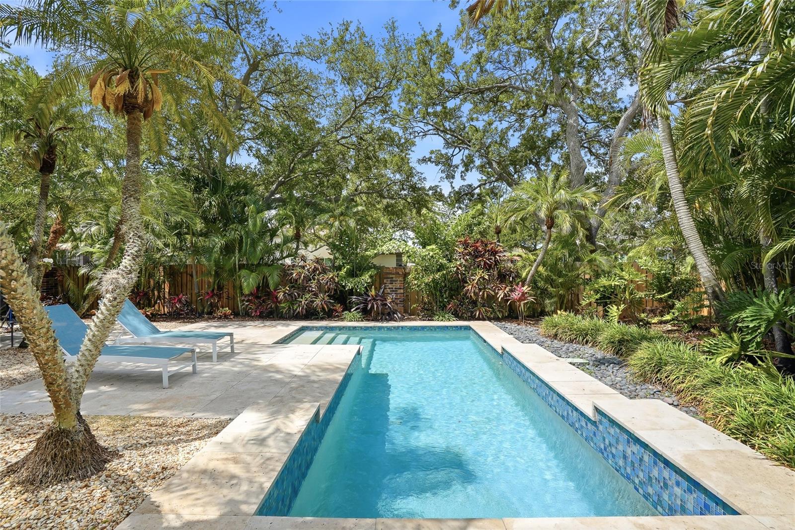 Surrounded by a fully fenced backyard filled with Florida native and tropical plants, the setting feels serene, secluded, and resort-inspired.