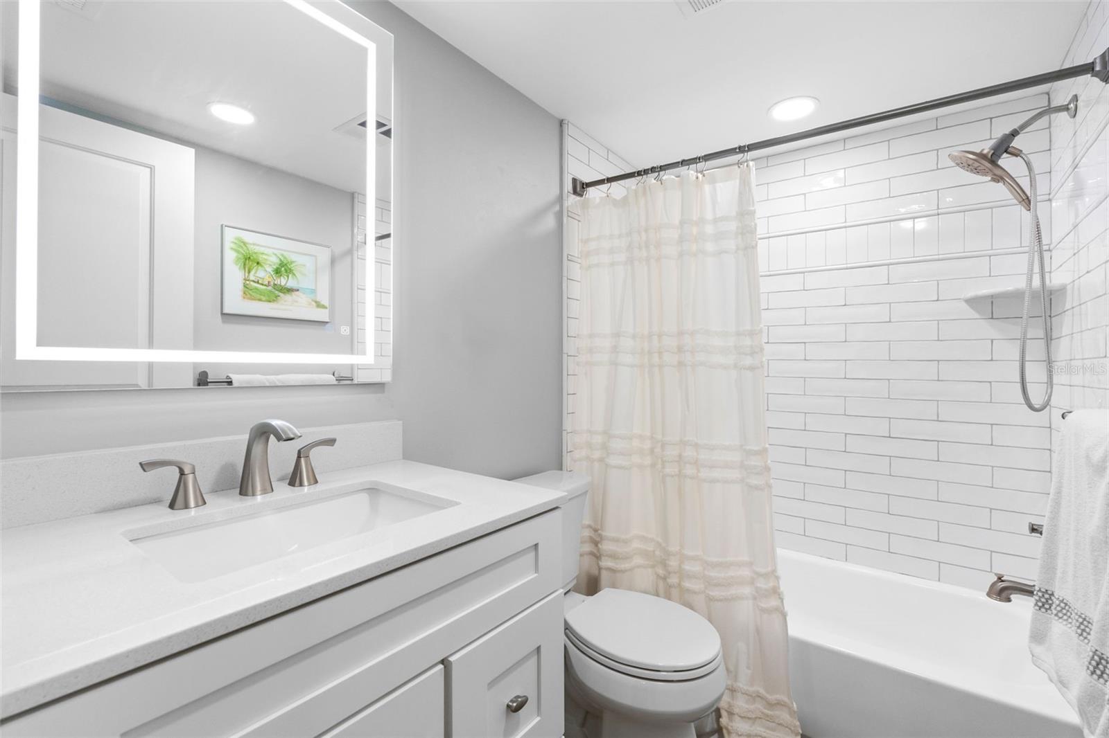 2nd Bathroom is roomy with light up Mirror, subway tile, and luxury vinyl flooring