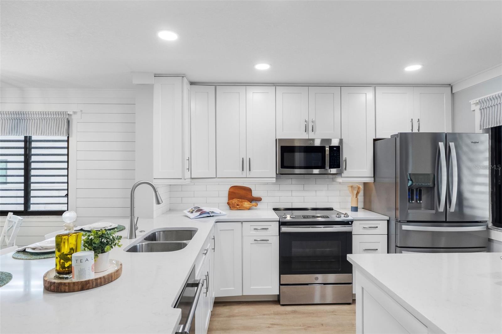 Kitchen has quartz countertops, Shaker cabinets, stainless appliances, and counter bar