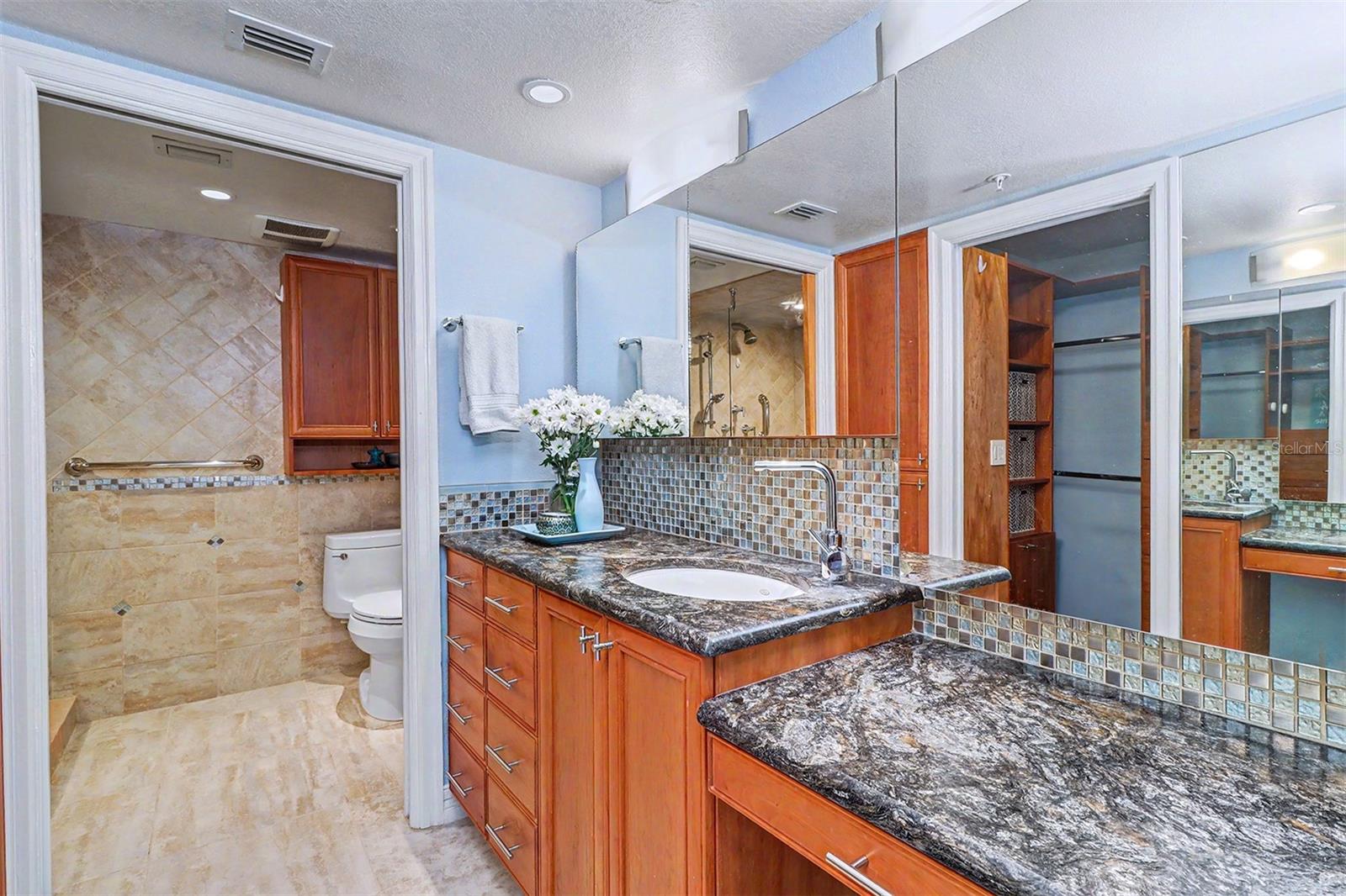Primary Suite Bath is thoughtfully appointed with separate vanity areas, providing both privacy and convenience, and includes a built-in makeup table with granite countertops.