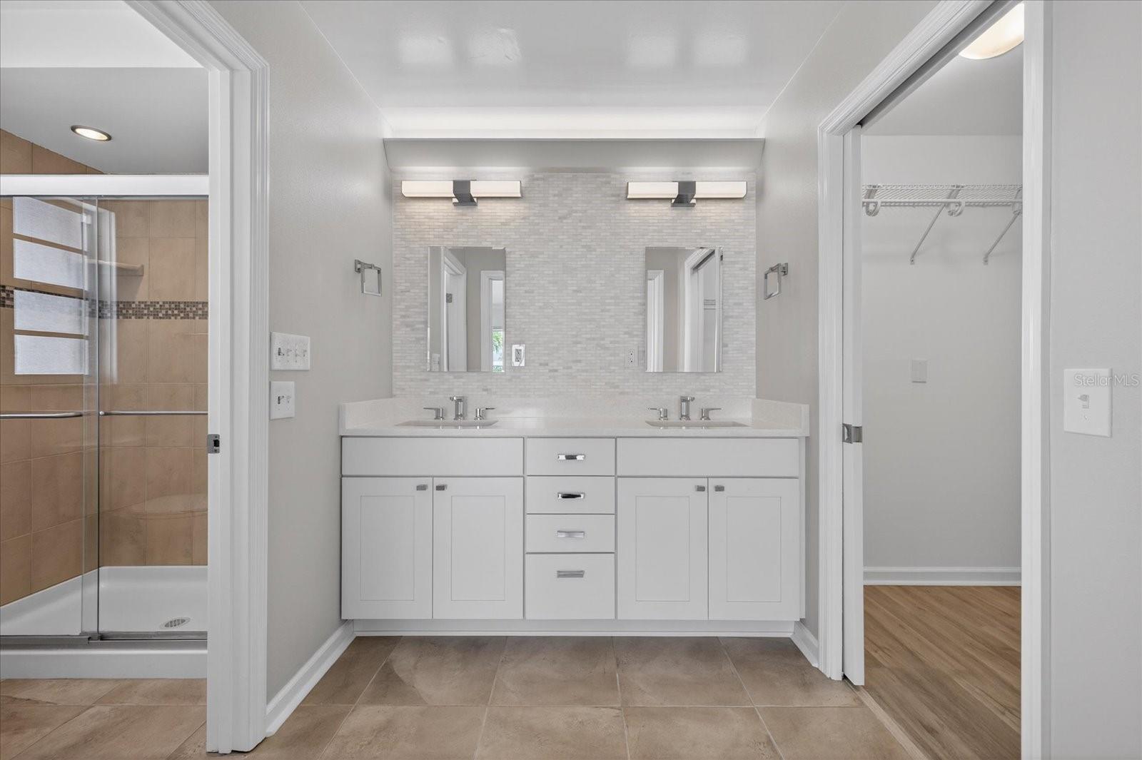 Primary bathroom features double sinks and a walk-in closet