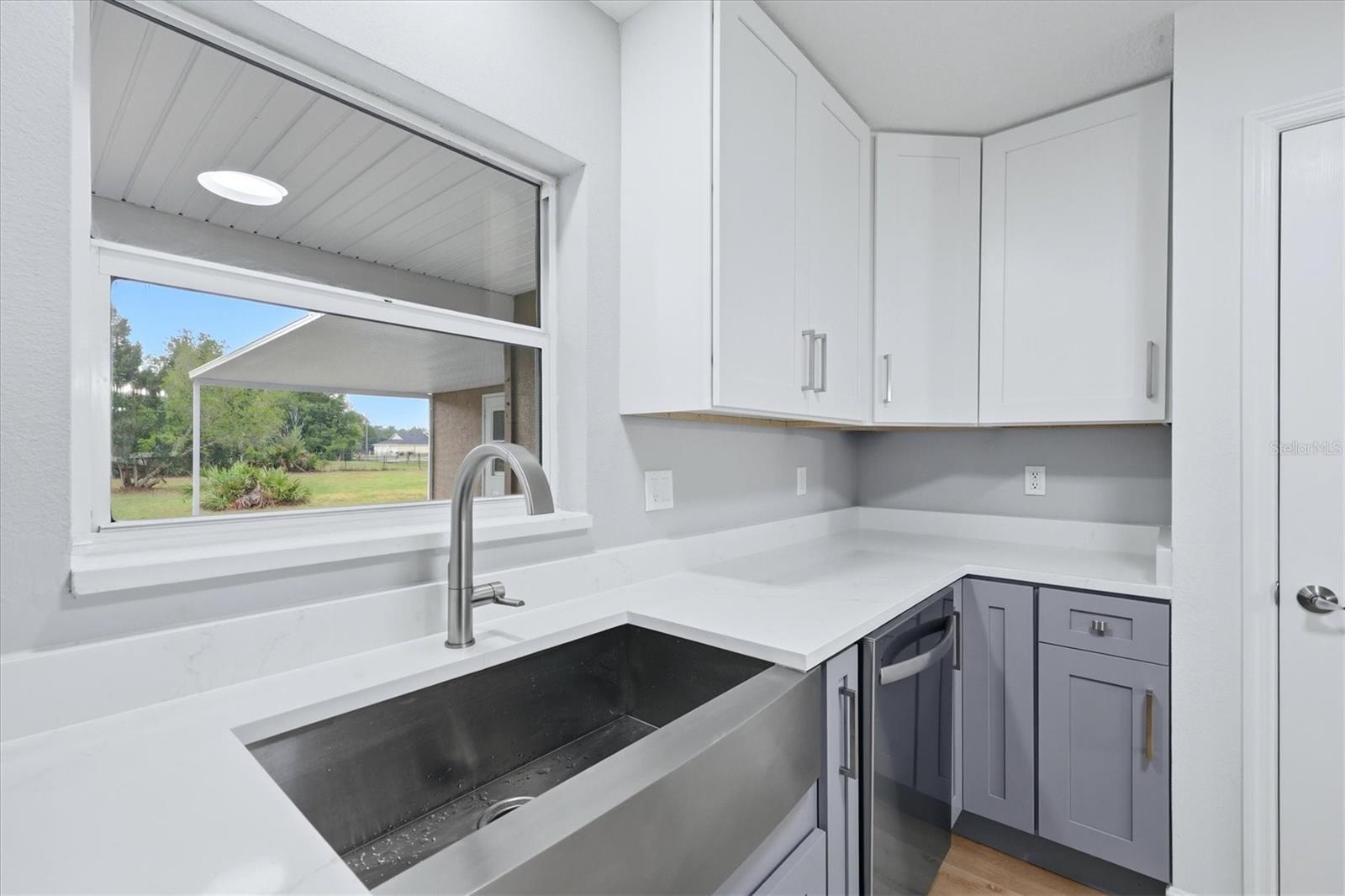 Deep stainless-steel farm style sink with Delta faucet featuring a virtually un-noticeable pull-out nozzle with sprayer