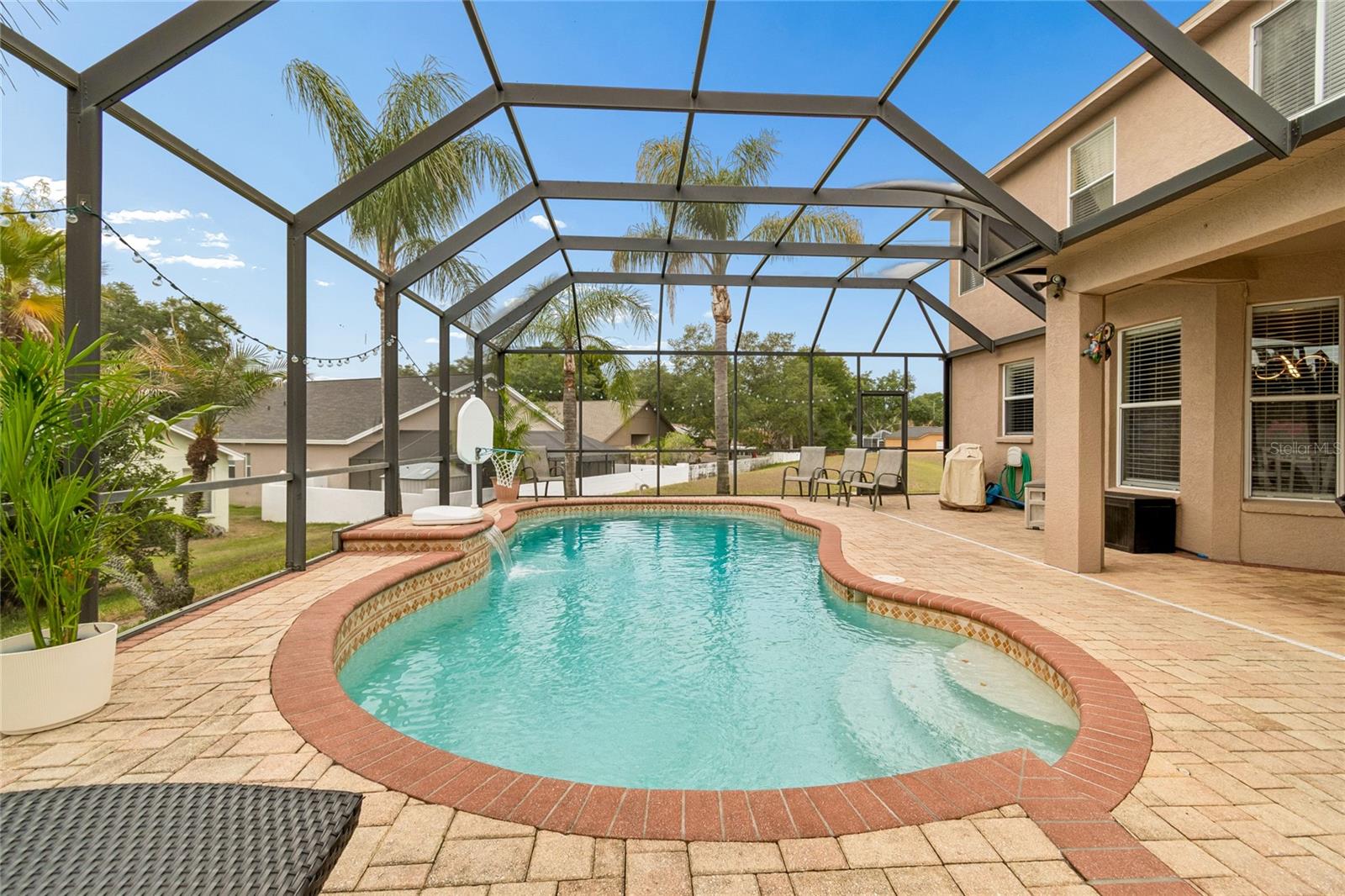 Featuring a tranquil waterfall, expansive paver deck, and multiple seating and gathering areas