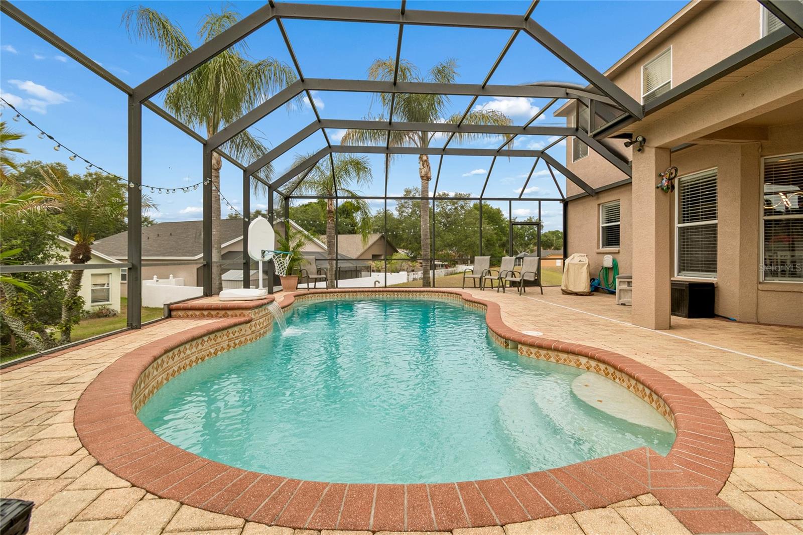 Featuring a tranquil waterfall, expansive paver deck, and multiple seating and gathering areas