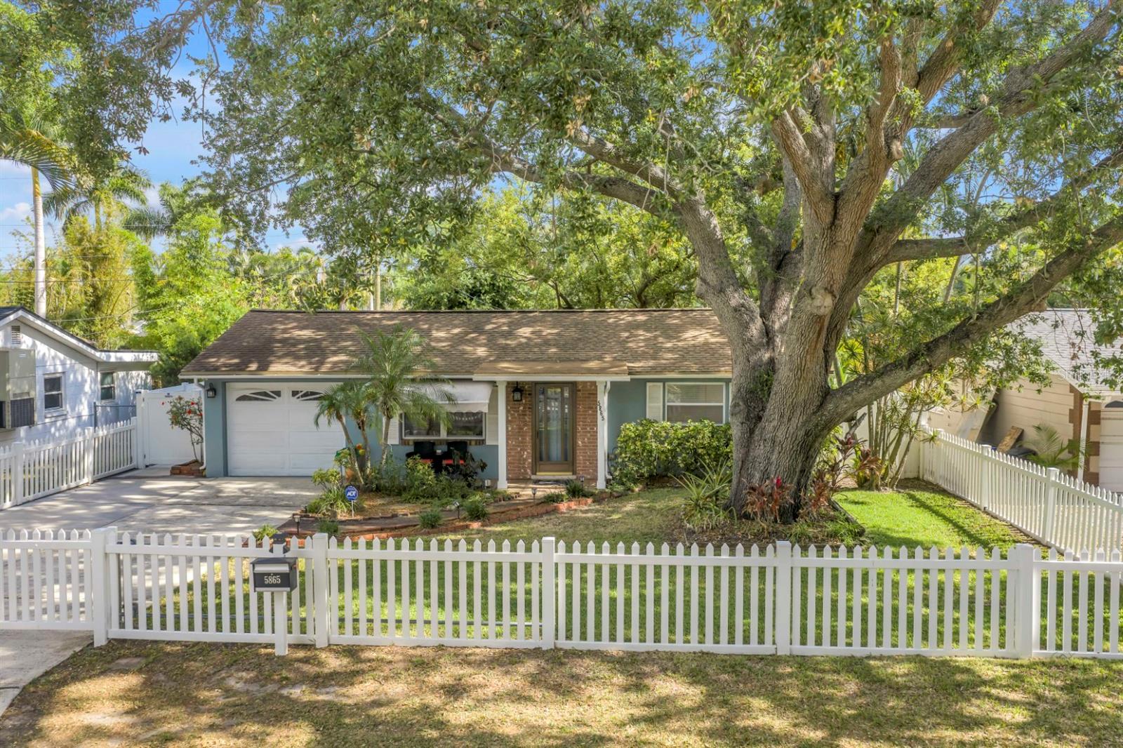 Framed by a classic white picket fence, this inviting front yard offers privacy, charm, and timeless appeal