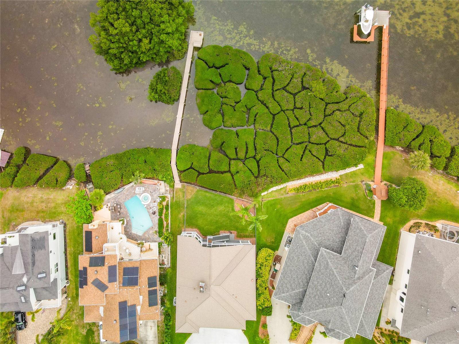 Experience nature's canopy from above as the drone captures the breathtaking view of lush mangroves gracefully enveloping the property, creating a serene oasis that beautifully contrasts with the waters below.