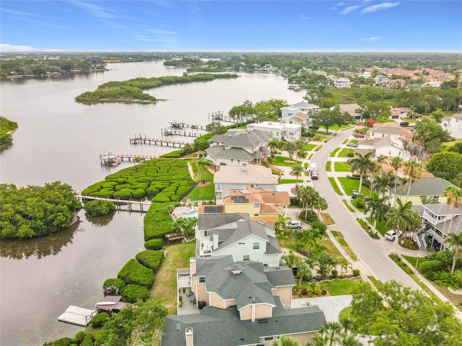 Soaring above, this aerial view captures the stunning waterfront home nestled among lush green mangroves, showcasing the perfect blend of serenity and natural beauty in coastal living