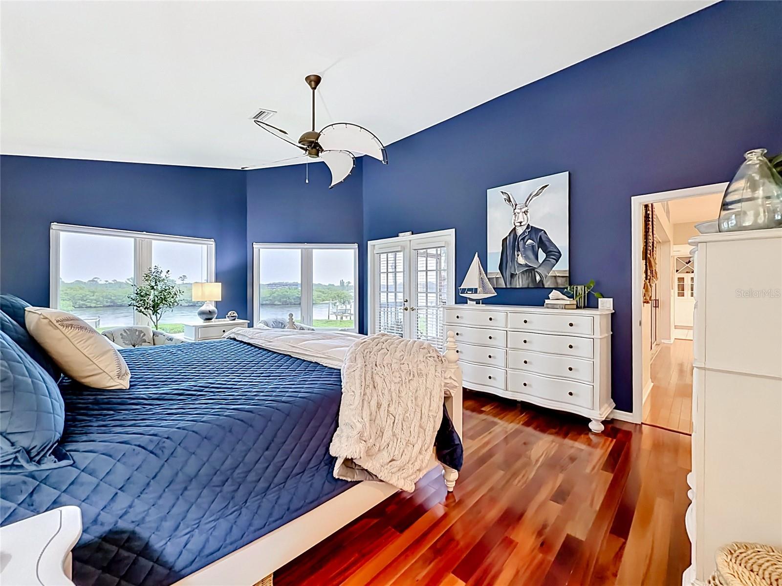 With high ceilings and a refreshing blue palette, this primary bedroom perfectly complements the stunning emerald waters outside—truly a breathtaking escape