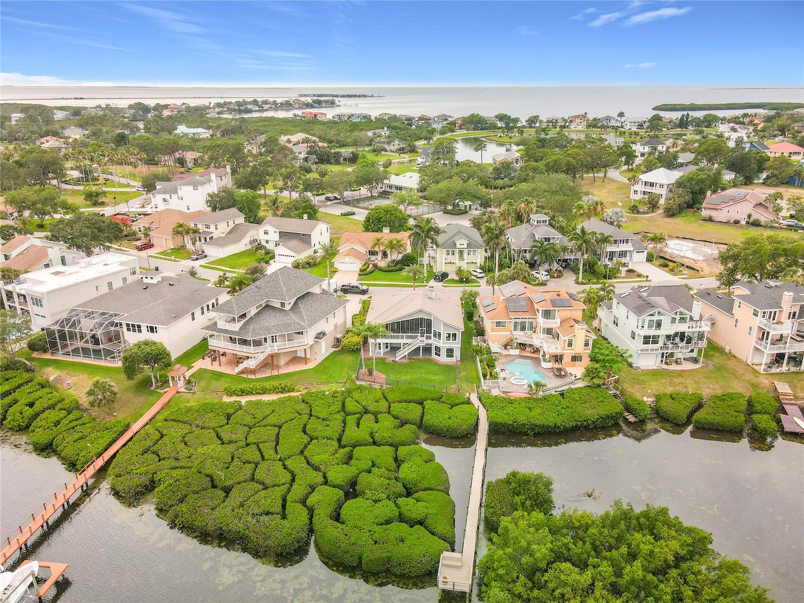 From above, witness the breathtaking harmony of this waterfront home nestled within lush greenery, a true representation of serene coastal life and its enchanting surroundings.
