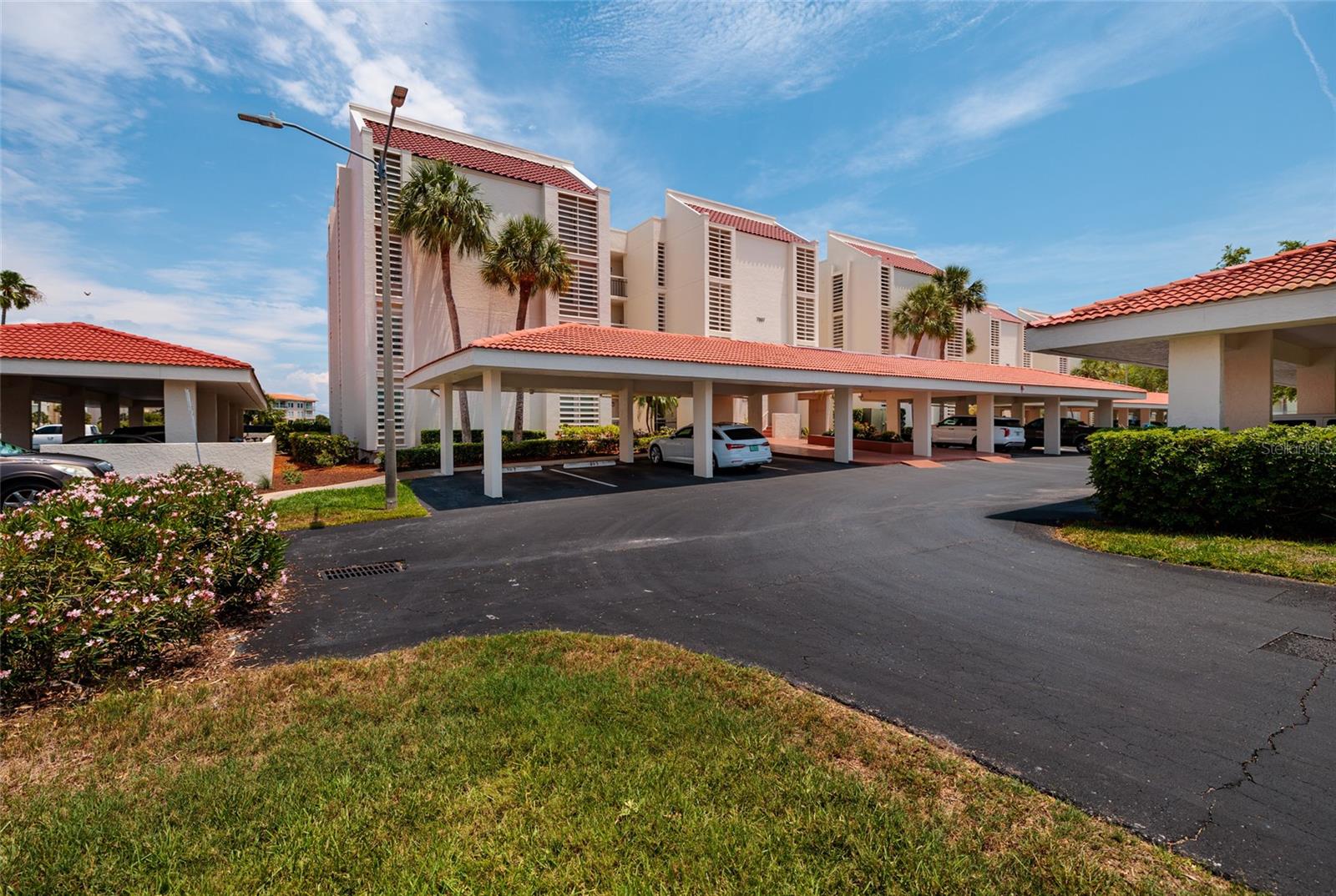 West view of building entrance.  Unit 107 parking space at end with extra space for driver exit and items; just steps to building entrance/elevators