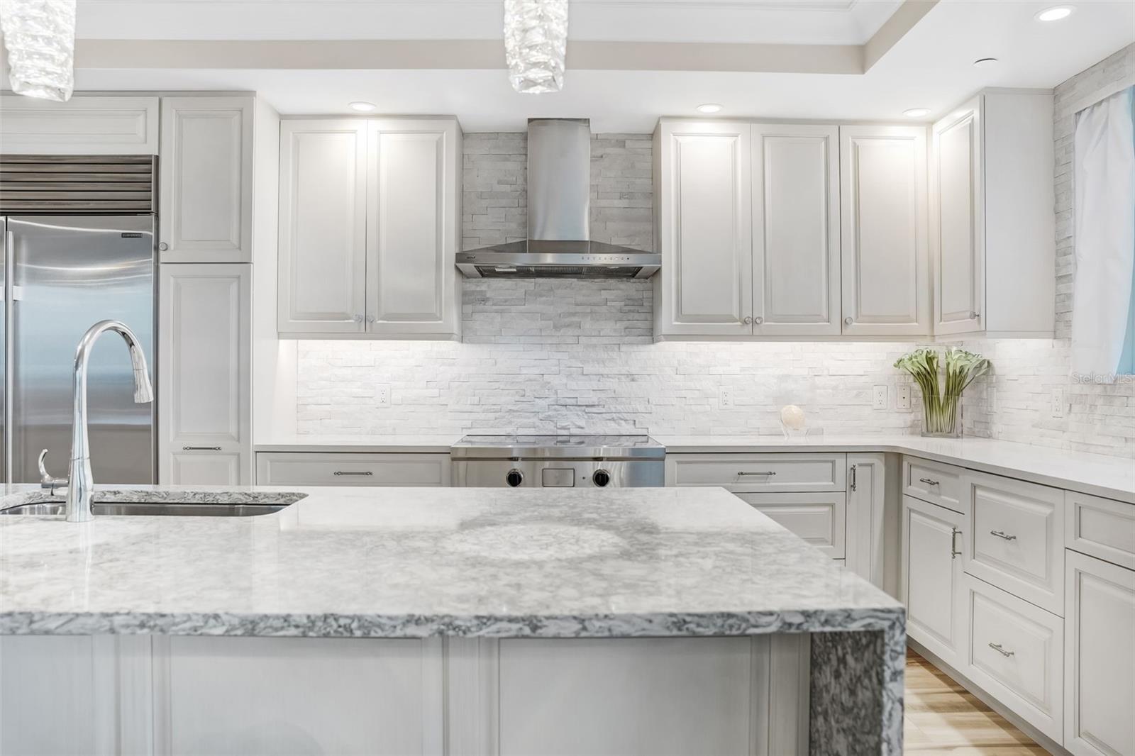 This is a closer look at the hand picked light fixtures for the kitchen island and beautiful backsplash and Wolf range & hood.