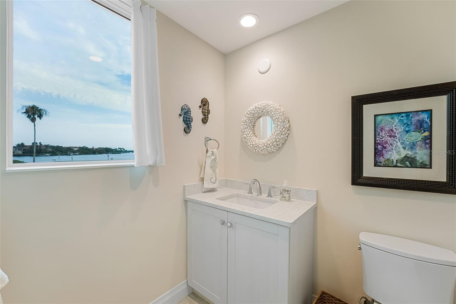 This ensuite bathroom has nice natural light with a window that has a view of the water