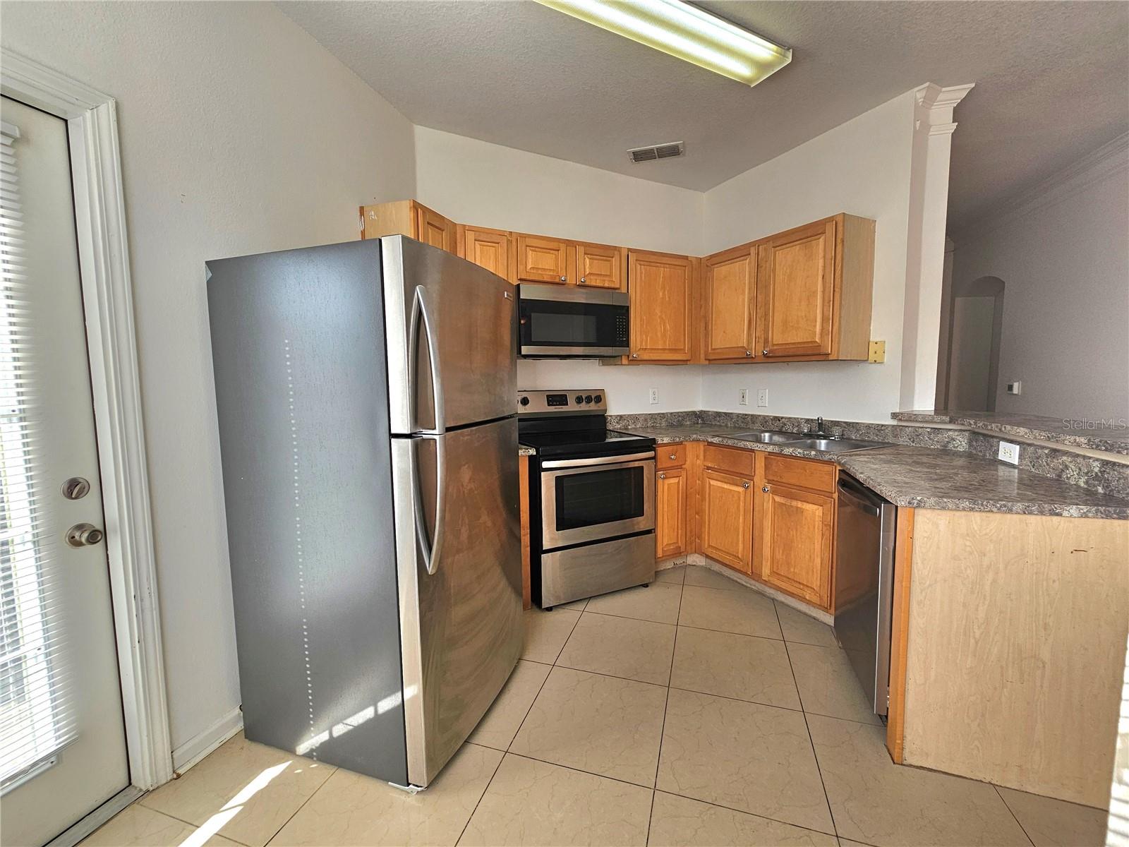 Kitchen side door, stainless steel appliances, refrigerator, stove, microwave, dishwasher Open to the living room