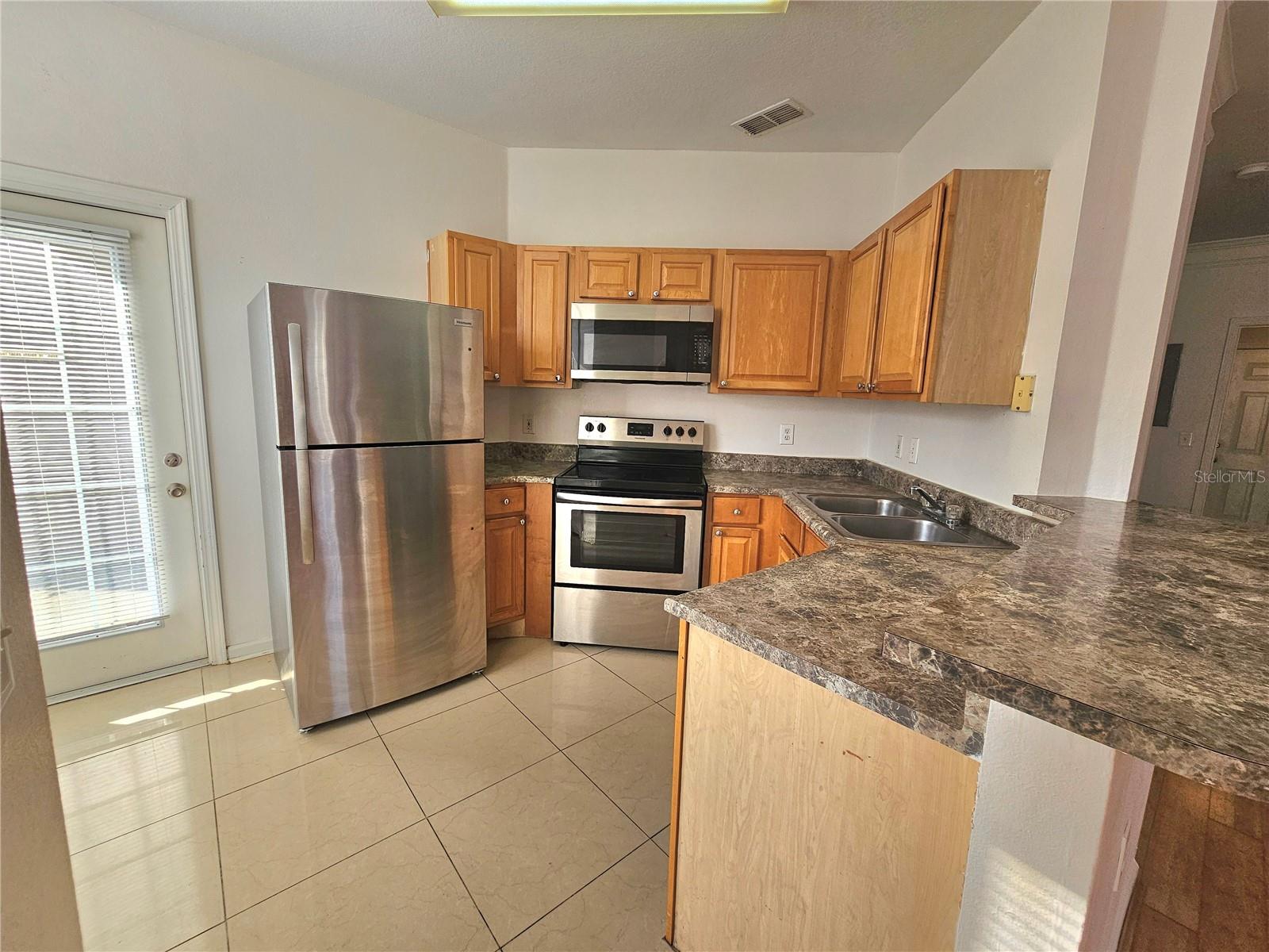 Kitchen side door, stainless steel appliances, refrigerator, stove, microwave and side door