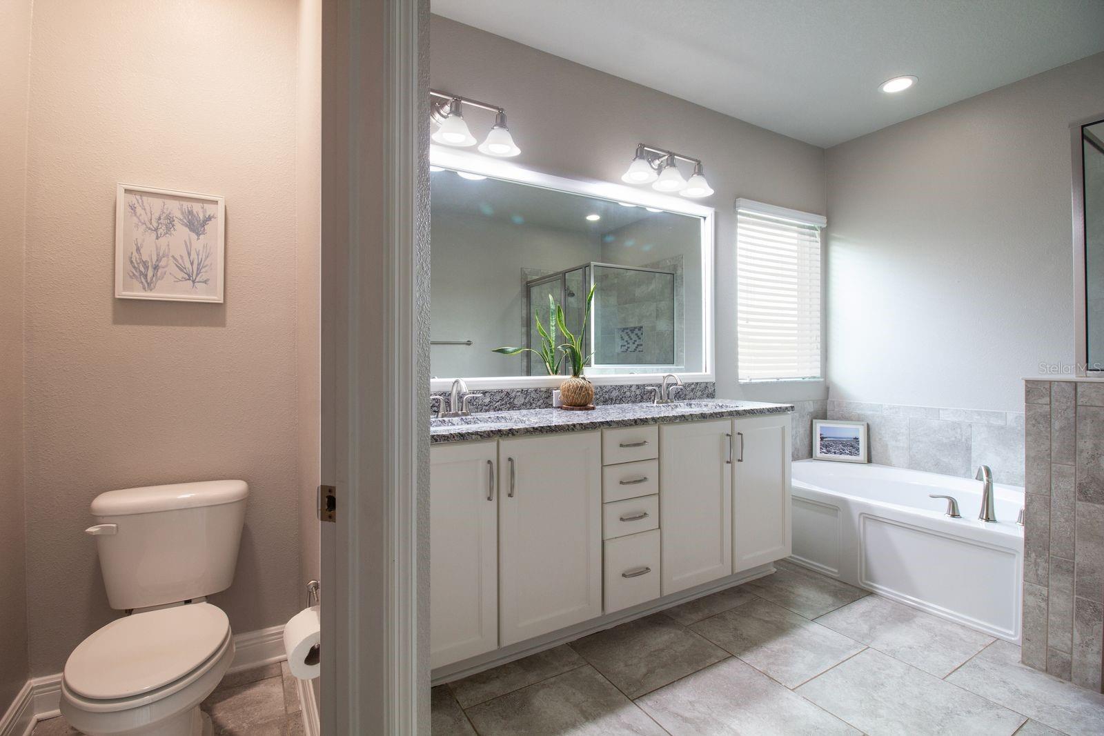 Primary bathroom features stone tops, soaker garden tub and walk in shower