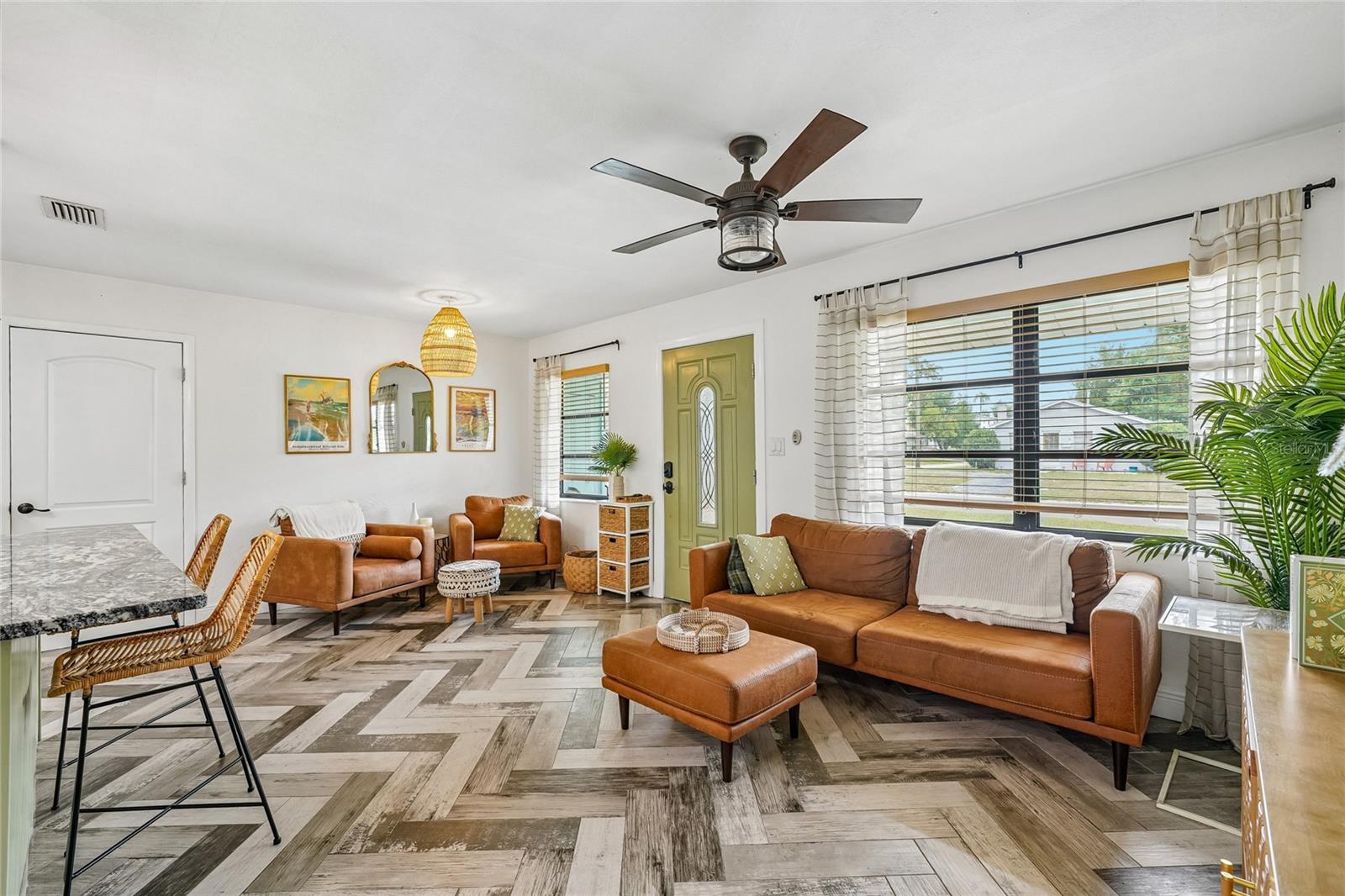 Living Room — Second view of the living area highlights the herringbone tile flooring and ceiling fan. Open sightlines connect to the kitchen.