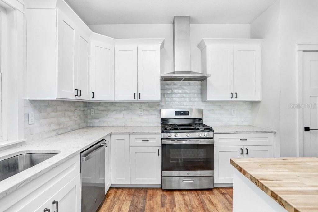 View of stove and hood and cabinets