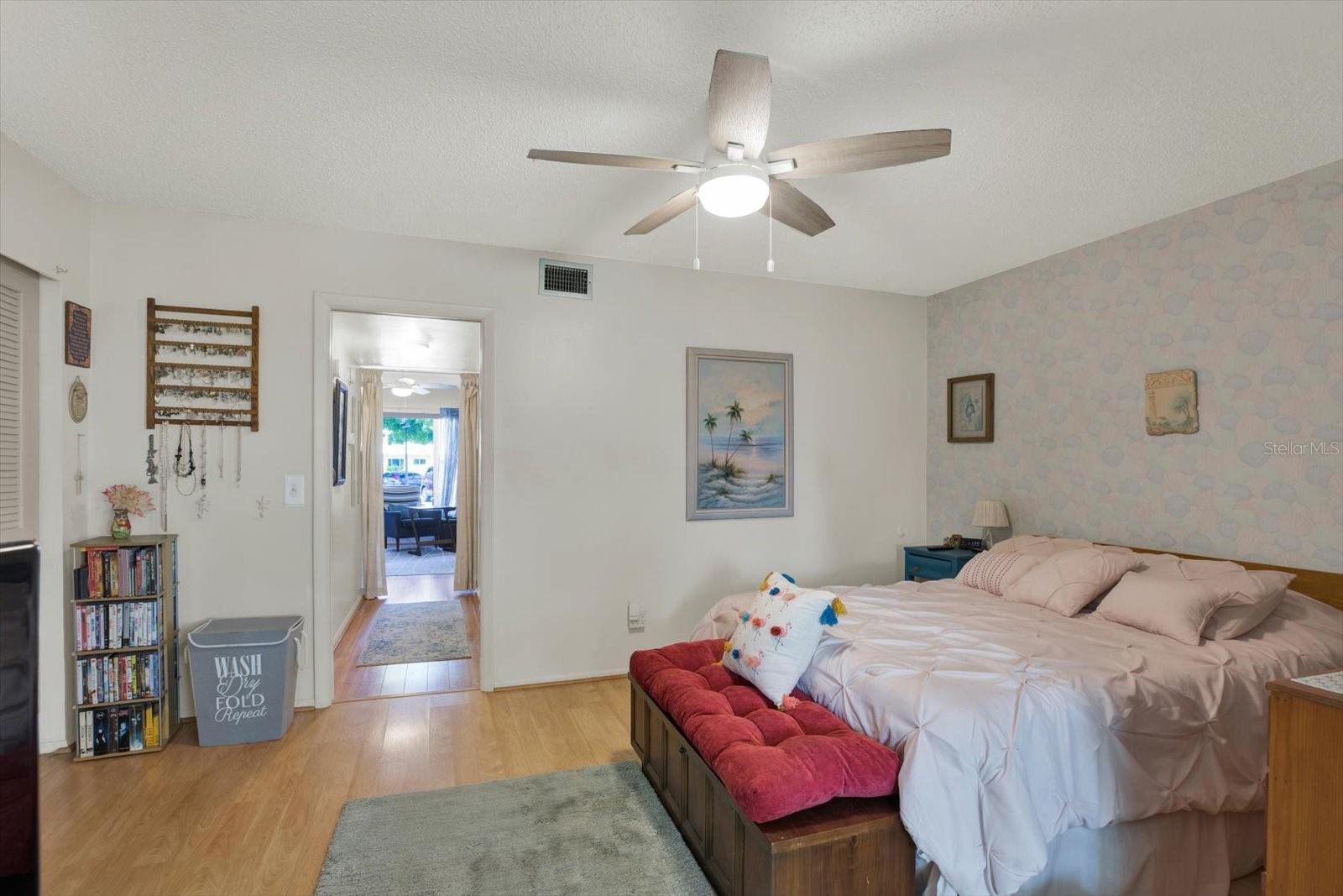 Primary bedroom with accent wallpaper and ceiling fan